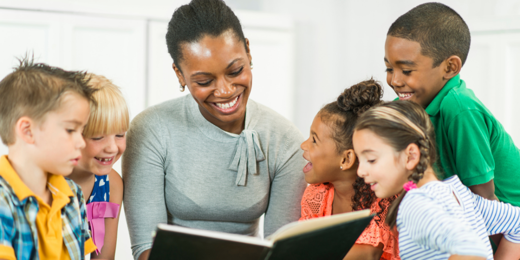 Child care provider smiling and reading to young children