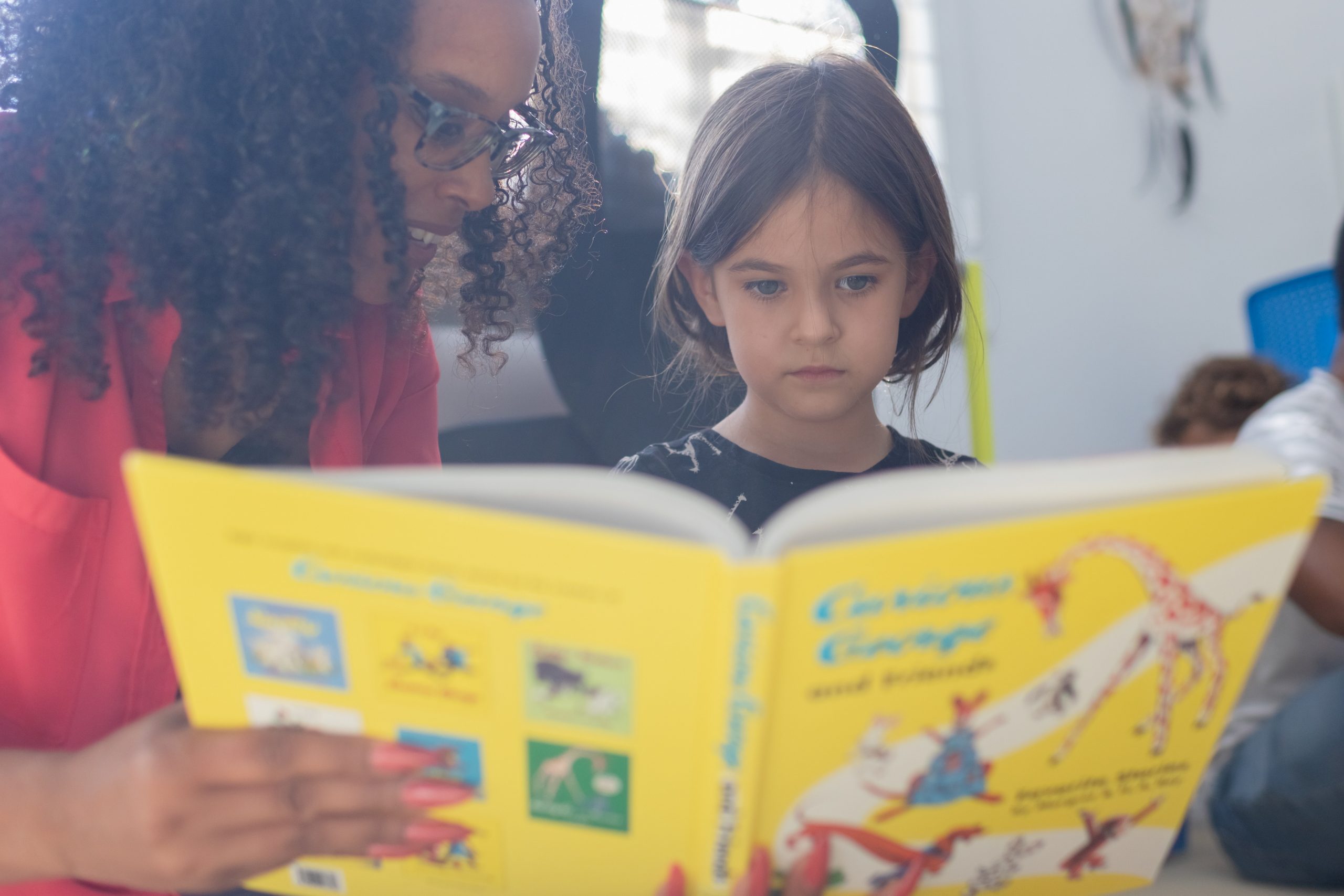 An adult reading a book to a child.
