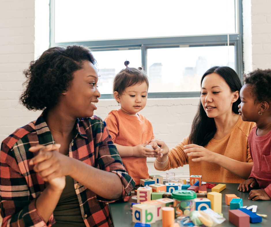 Two adults and two toddlers interacting with each other.