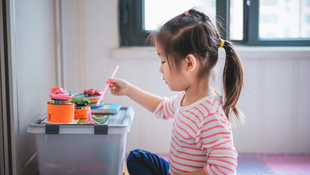 A child sitting down and playing with toys on a box. 