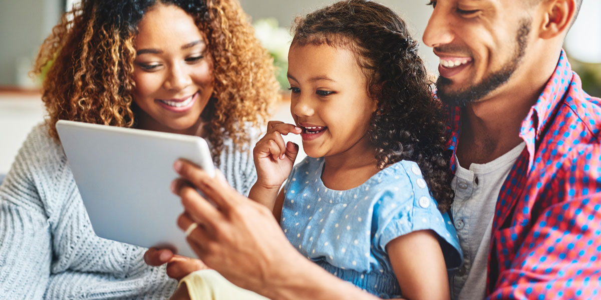 photo of an african-american couple looking at a tablet with their young daughter