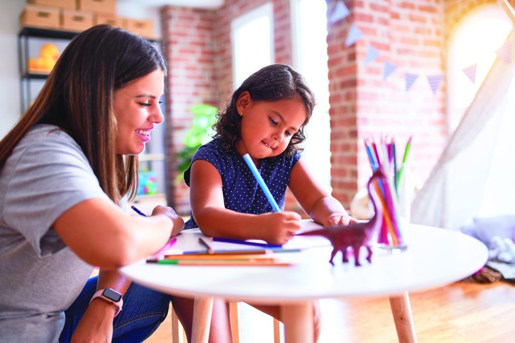 An educator observing a child using colored pencils.