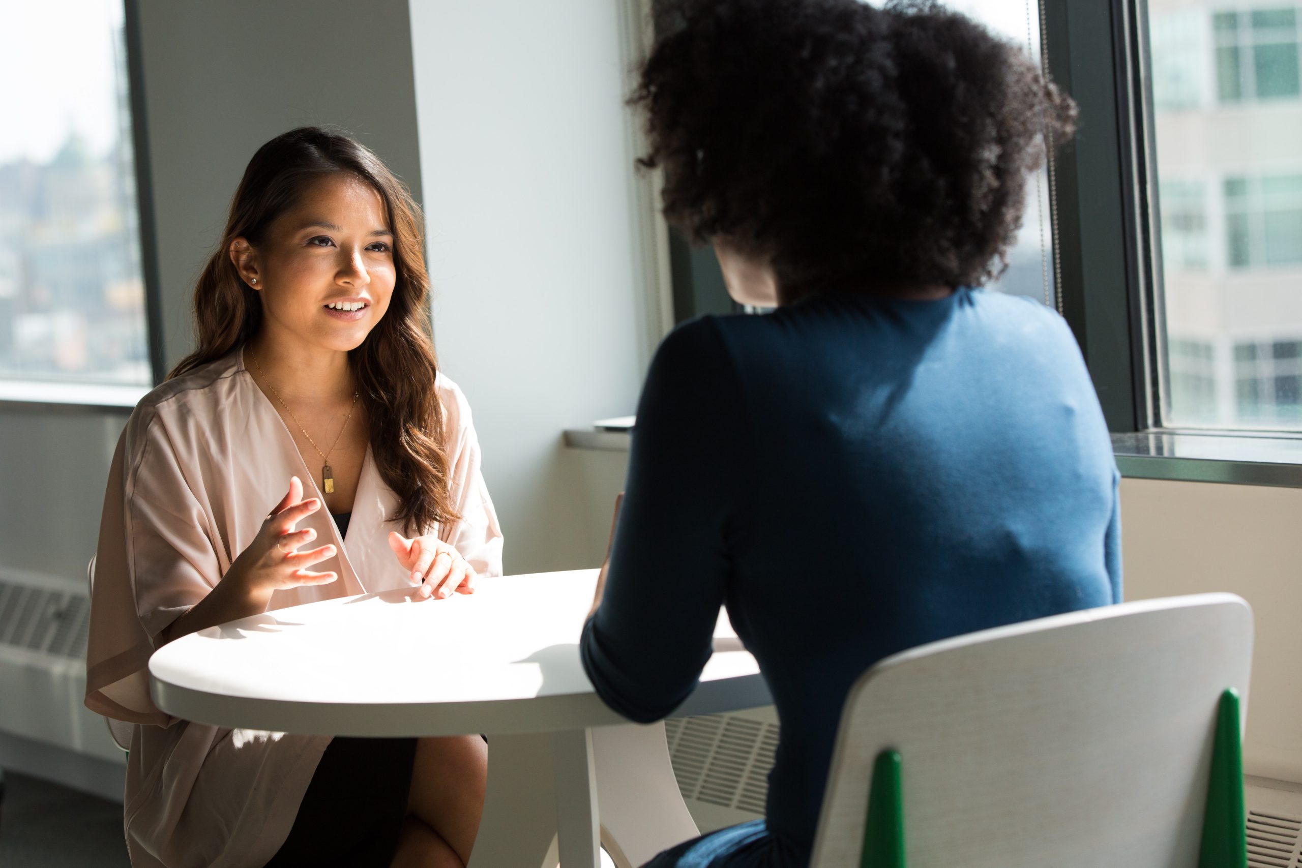 Two adults sitting at a table across from each other engaged in a conversation

