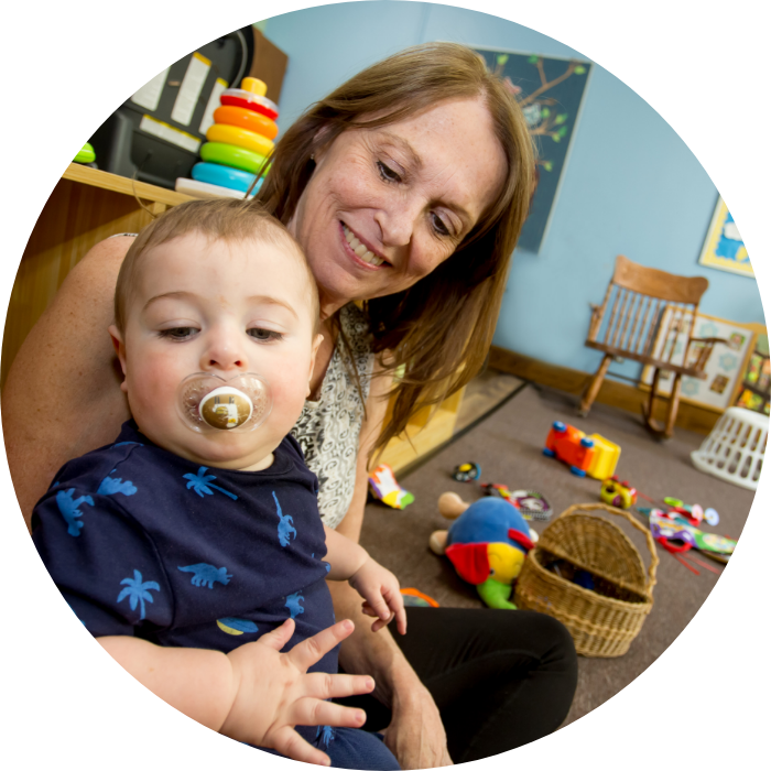 Educator holding infant with pacifier