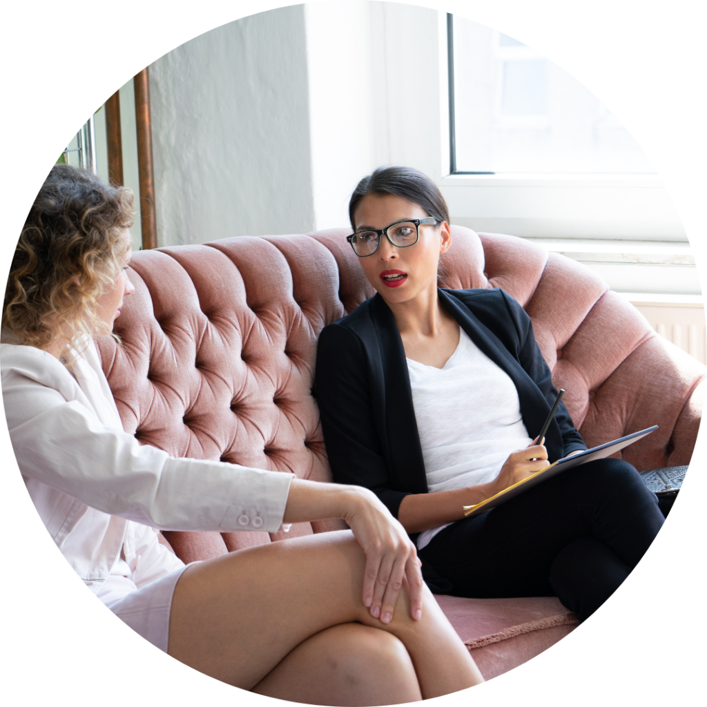 Two women in conversation while sitting on a couch.